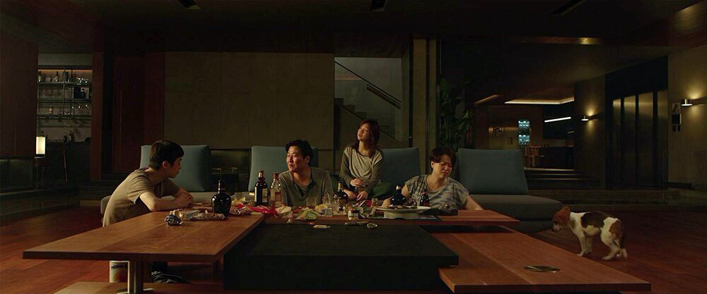 The Kim family celebrates their own cleverness in the Park family's living room. (L to R: Choi Woo-shik, Song Kang-ho, Park So-dam, and Jang Hye-jin).