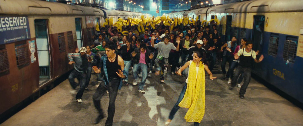 Photo of Dev Patel as Jamal and Freida Pinto as Latika leading the dancers in a Bollywood-style finale.